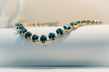 A delicate gold bracelet with dark blue gems