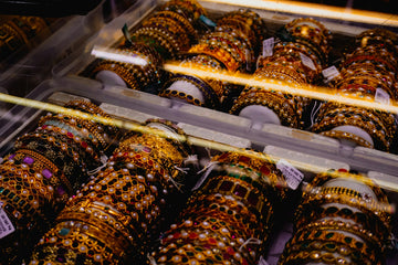 Rows of ornate, jeweled bangles displayed in a case