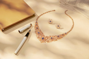 A delicate necklace and earrings with a pen and notebook