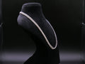 Pearl necklace on a black mannequin bust against a dark background